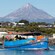 A tour boat setting off in a port in front of oceanside houses and Mount Taranaki